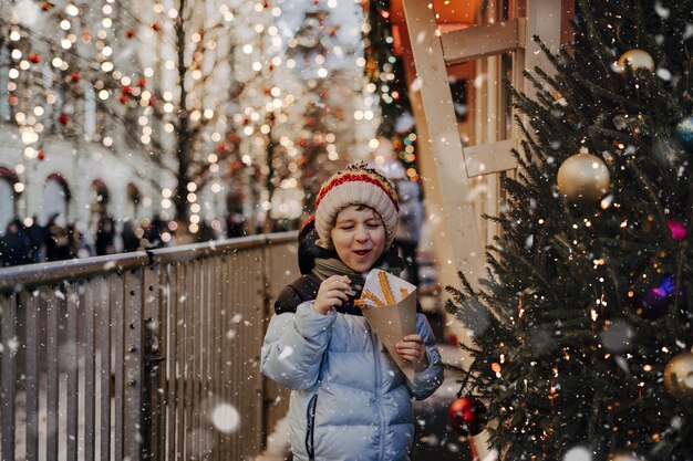 Petit garçon mignon et drôle qui mange des churros lors d'une foire traditionnelle de Noël dans la neige.