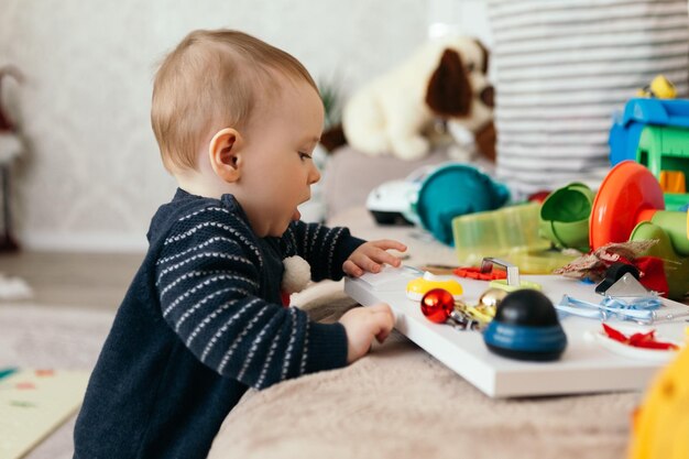 Petit garçon mignon enfant ludique tout-petit jouant différents tas de jouets colorés boules décorées