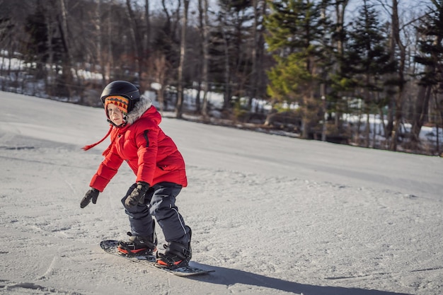 Petit garçon mignon faisant du snowboard Activités pour enfants en hiver Sports d'hiver pour enfants