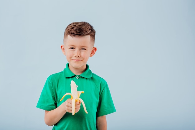 Petit garçon mignon mangeant une banane fraîche