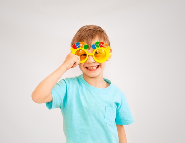 Petit garçon mignon portant des lunettes de fête avec texte joyeux anniversaire. garçon à lunettes jaunes