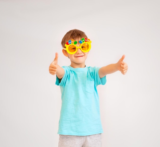 Petit garçon mignon portant des lunettes de fête avec texte joyeux anniversaire. garçon à lunettes jaunes