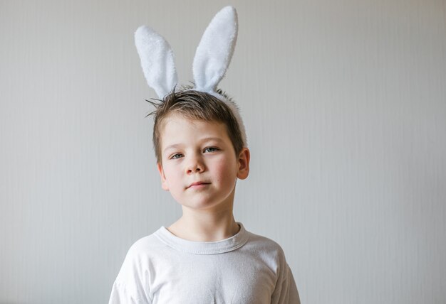 Petit garçon mignon portant des oreilles de lapin de Pâques, sourire