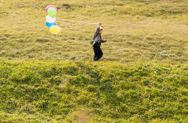 Petit garçon mignon sur le pré d'herbe avec des ballons