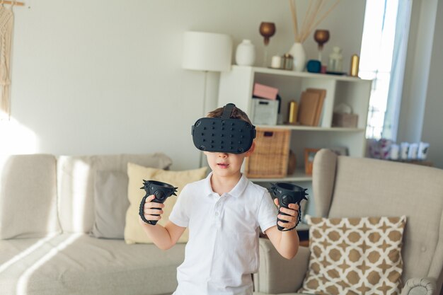 Petit garçon mignon regarde la réalité virtuelle avec des lunettes.