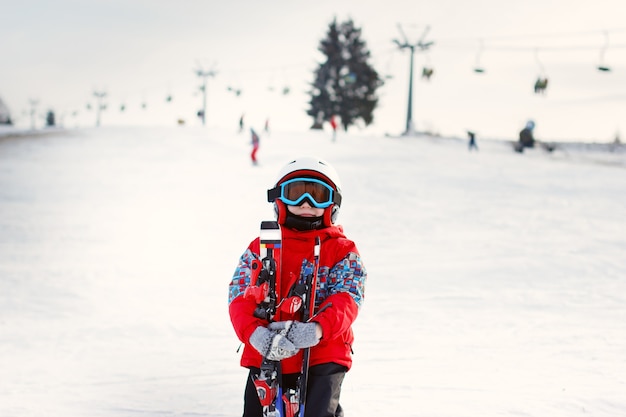 Photo petit garçon mignon avec des skis et une tenue de ski