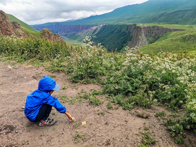 Un petit garçon nourrit des gophers dans la gorge de JilySu KabardinoBalkaria Russie juin 2021