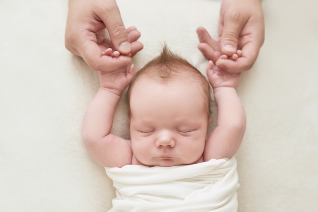 Petit garçon nouveau-né dans les mains de papa dormant sur fond blanc. Concept de médecine et de santé, maternité et paternité heureuses. Maternité et clinique. Fête des pères et mères