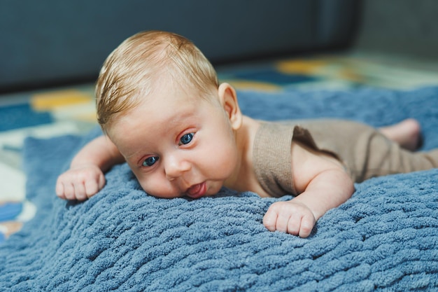 Un petit garçon nouveau-né est allongé sur une couverture à tricot grise Portrait d'un bébé d'un mois