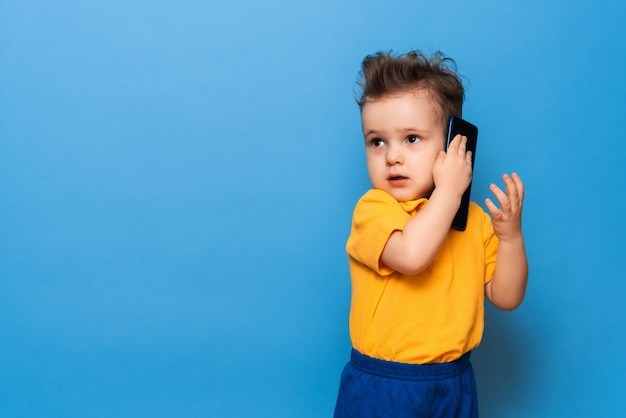 Un petit garçon parle sur un téléphone mobile