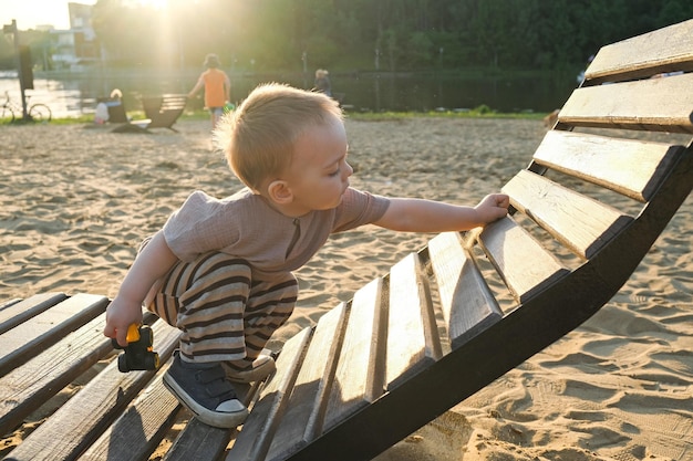 Le petit garçon passe du temps sur la plage au bord de la rivière en été