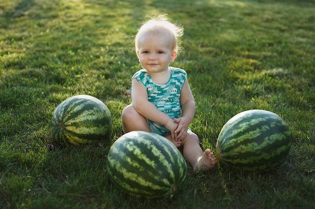 Petit garçon avec une pastèque assis sur l'herbe