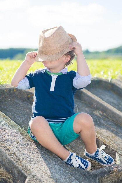 Un petit garçon portant un chapeau s'amuse dans le parc par une journée ensoleillée d'été