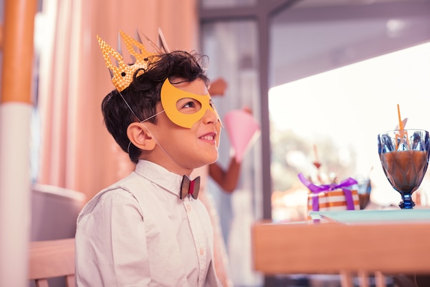 Petit garçon portant un masque mignon tout en étant à la fête d'anniversaire