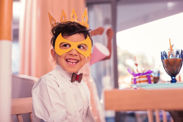 Petit garçon portant un masque mignon tout en étant à la fête d'anniversaire