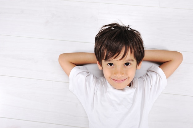 Petit garçon pose détendu sur un sol blanc à la maison