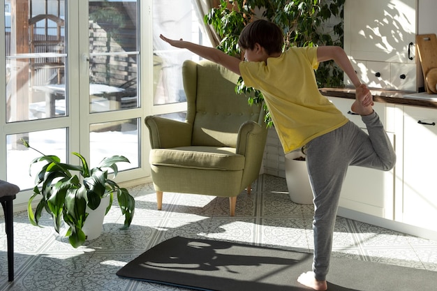 Photo petit garçon pratiquant le yoga, l'étirement, la remise en forme à la maison, l'éducation en ligne, l'entraînement aérobie.