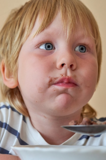 Le petit garçon prend le petit déjeuner avec des boules de chocolat avec du lait