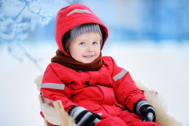 Petit garçon profitant d&#39;une promenade en traîneau. Enfant en traîneau. Enfant en bas âge sur une luge. Les enfants jouent dehors dans la neige. Enfants traîneau à winter park. Amusement actif en plein air pour des vacances en famille.