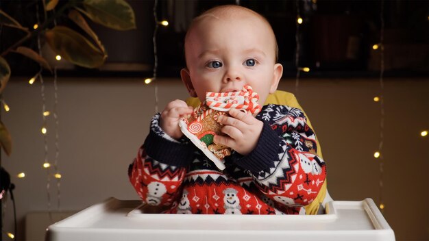 Petit garçon en pull de Noël jouant avec une maison en pain d'épice jouet