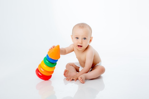 Un petit garçon avec une pyramide multicolore est isolé sur un fond blanc ;