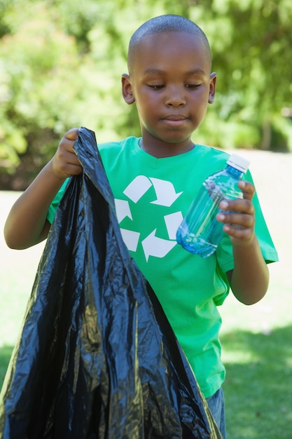 Petit garçon en recyclage tshirt ramasser les ordures