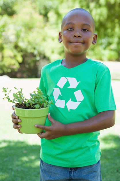 Petit garçon en recyclage tshirt tenant plante en pot