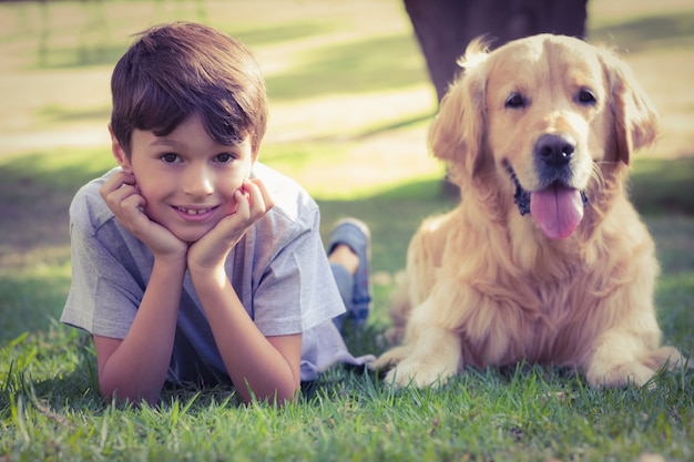 Photo petit garçon regardant la caméra avec son chien dans le parc