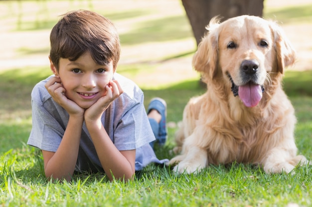 Photo petit garçon en regardant la caméra avec son chien dans le parc