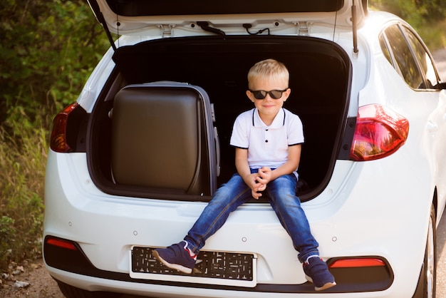 Petit garçon reposant sur le bord de la route lors d'un road trip. Road trip avec des enfants.