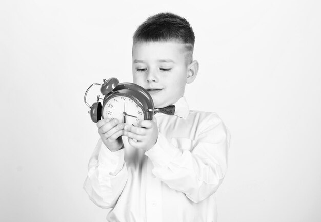 Petit Garçon Avec Réveil. Le Temps De Se Détendre. Enfant En Smoking. Enfance Heureuse. L'heure De La Fête. Homme D'affaire. Vêtements De Cérémonie. Enfant Heureux Avec Horloge Rétro En Noeud Papillon. Gestion Du Temps. Matin. Ambiance Matinale.