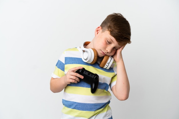 Petit garçon roux tenant une manette de jeu isolé sur fond blanc avec des maux de tête