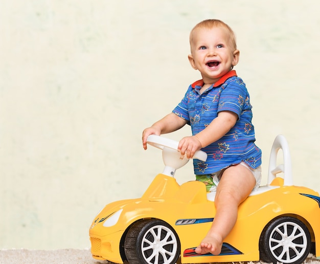 Petit garçon s'amusant sur une petite voiture jaune