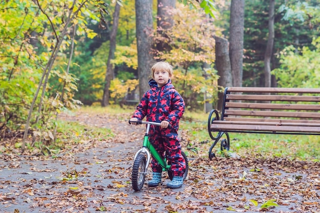 Petit garçon s'amusant à vélo dans la forêt d'automne. Mise au point sélective sur garçon