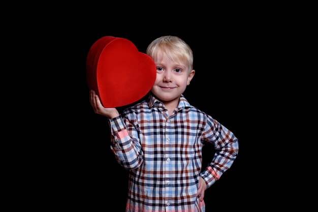 Petit garçon s'appuie contre sa joue en forme de coeur rouge boîte sur fond noir