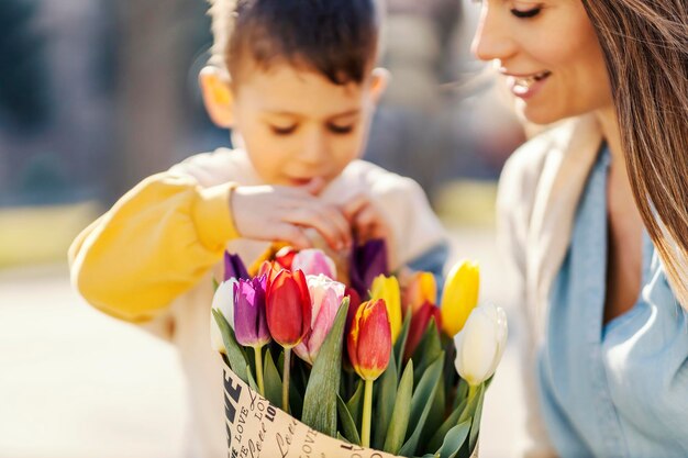 Un petit garçon avec sa mère et des fleurs pour la fête des mères