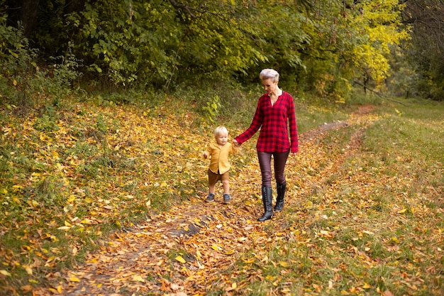 Petit garçon et sa mère sur fond d'automne avec des arbres dorés et rouges saison des fêtes de Thanksgiving