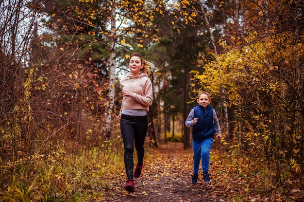 Petit garçon et sa soeur courir dans la forêt d&#39;automne