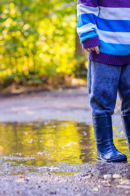 Un petit garçon saute dans une flaque d'eau.