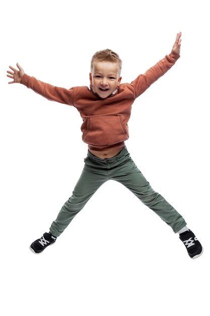 Le petit garçon saute émotionnellement. Liberté, joie et positivité. Isolé sur fond blanc. Verticale.