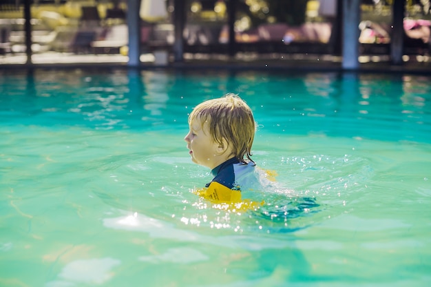 Petit garçon se baignant dans la piscine et souriant