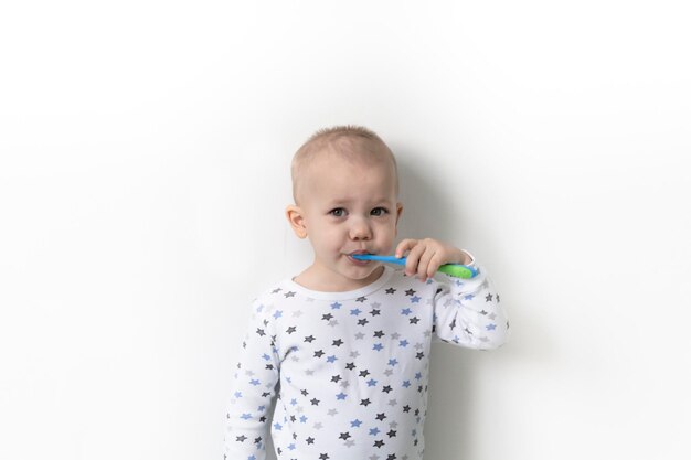 Un petit garçon se dresse contre les étoiles vêtues d'un t-shirt se brosse les dents et prend soin de sa bouche