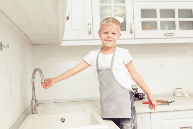 Petit garçon se lavant la main à la cuisine domestique