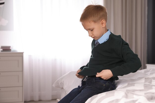 Petit garçon se prépare pour l'école dans la chambre