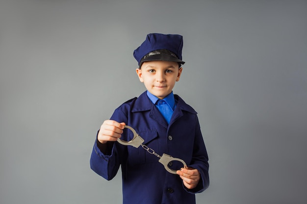 Le petit garçon se tient en costume de police et salue
