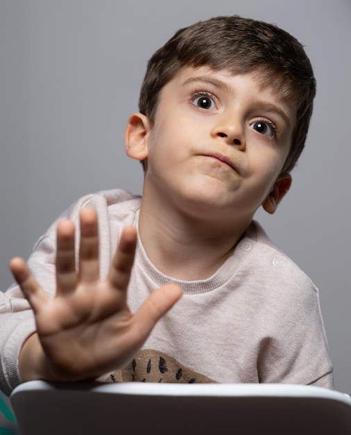 Petit garçon signe d'arrêt avec la main disant non exprimant la défense ou la restriction