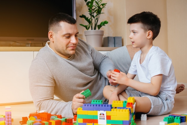 Un petit garçon avec son père est joué par un constructeur et construit une maison. Construction d'une maison familiale.