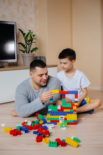 Un petit garçon avec son père est joué par un constructeur et construit une maison. Construction d'une maison familiale.