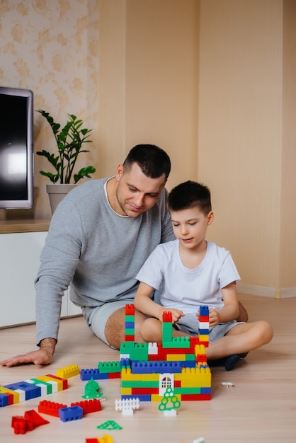 Un petit garçon avec son père est joué par un constructeur et construit une maison. Construction d'une maison familiale.