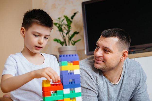 Un petit garçon avec son père est joué par un constructeur et construit une maison. Construction d'une maison familiale.